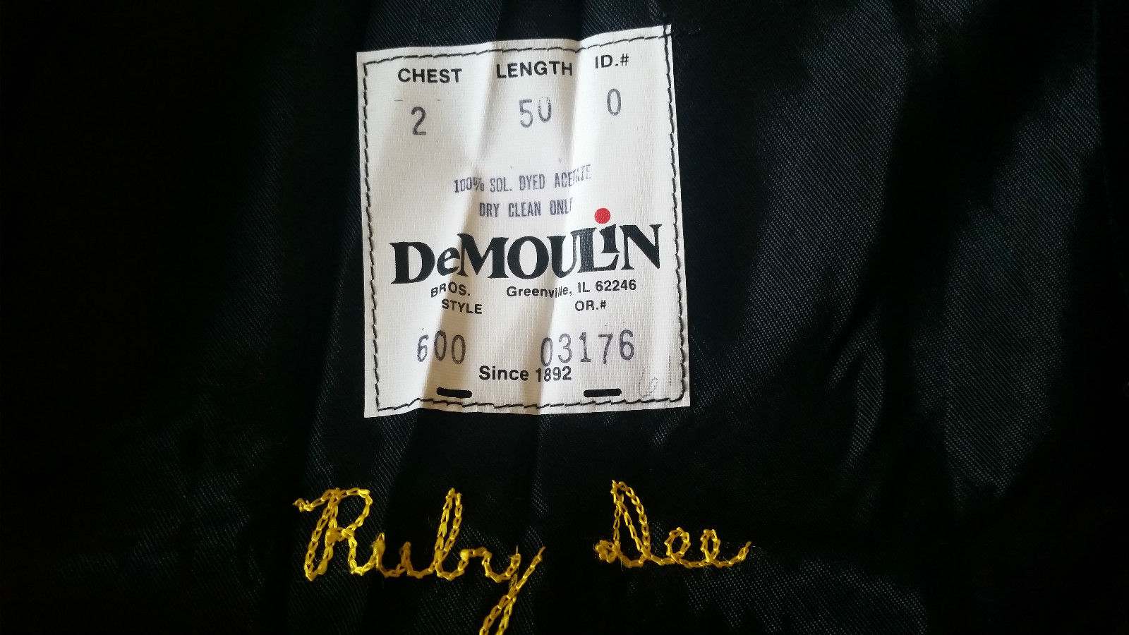 The DeMoulin manufacturing label inside the gown with Ms. Dee's name embroidered below it.