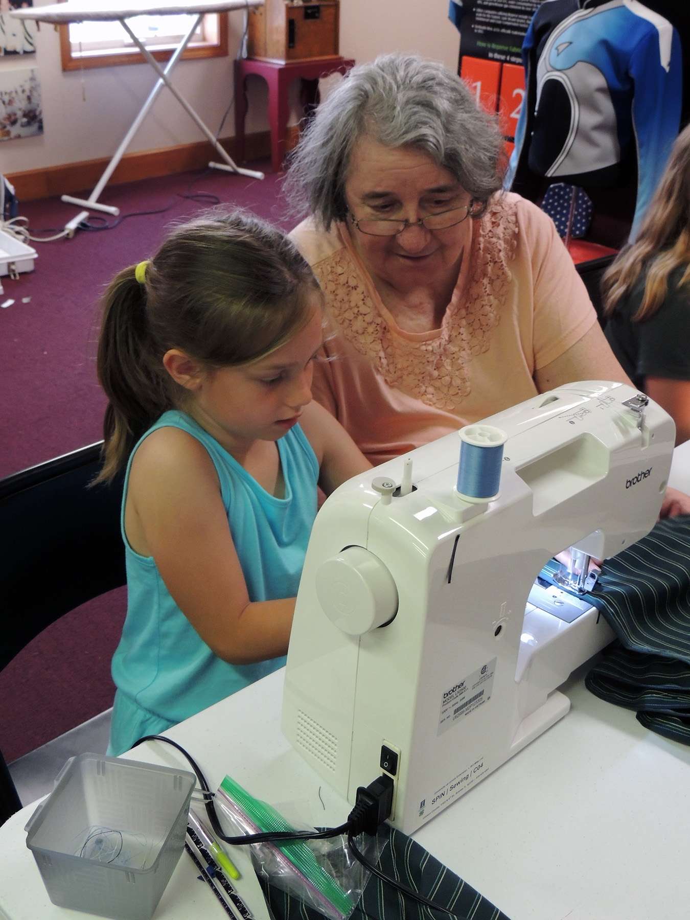 Carol Steinkamp works with one of the girls who attended the 4-H Sewing Workshop hosted by the DeMoulin Museum.
