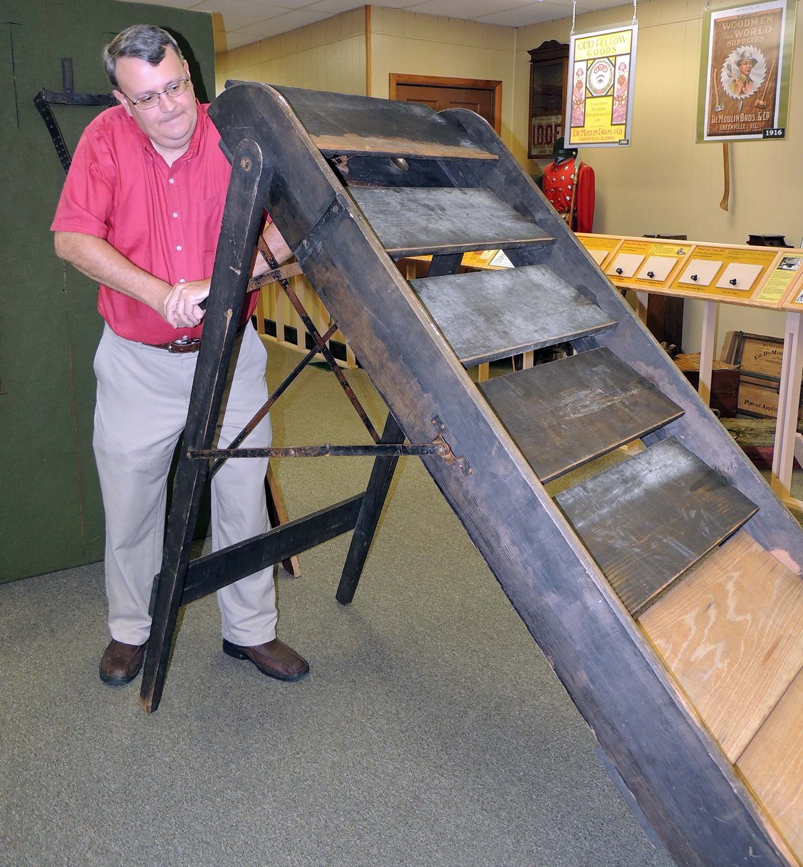 DeMoulin Museum curator demonstrates the trick to the sliding stairs.
