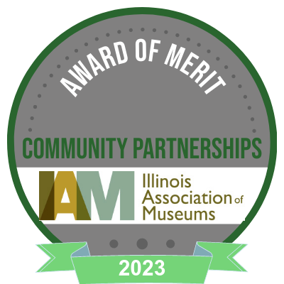 green ribbon and gray circle website badge recognizing Illinois Association of Museum's 2023 Award of Merit for Community Partnership