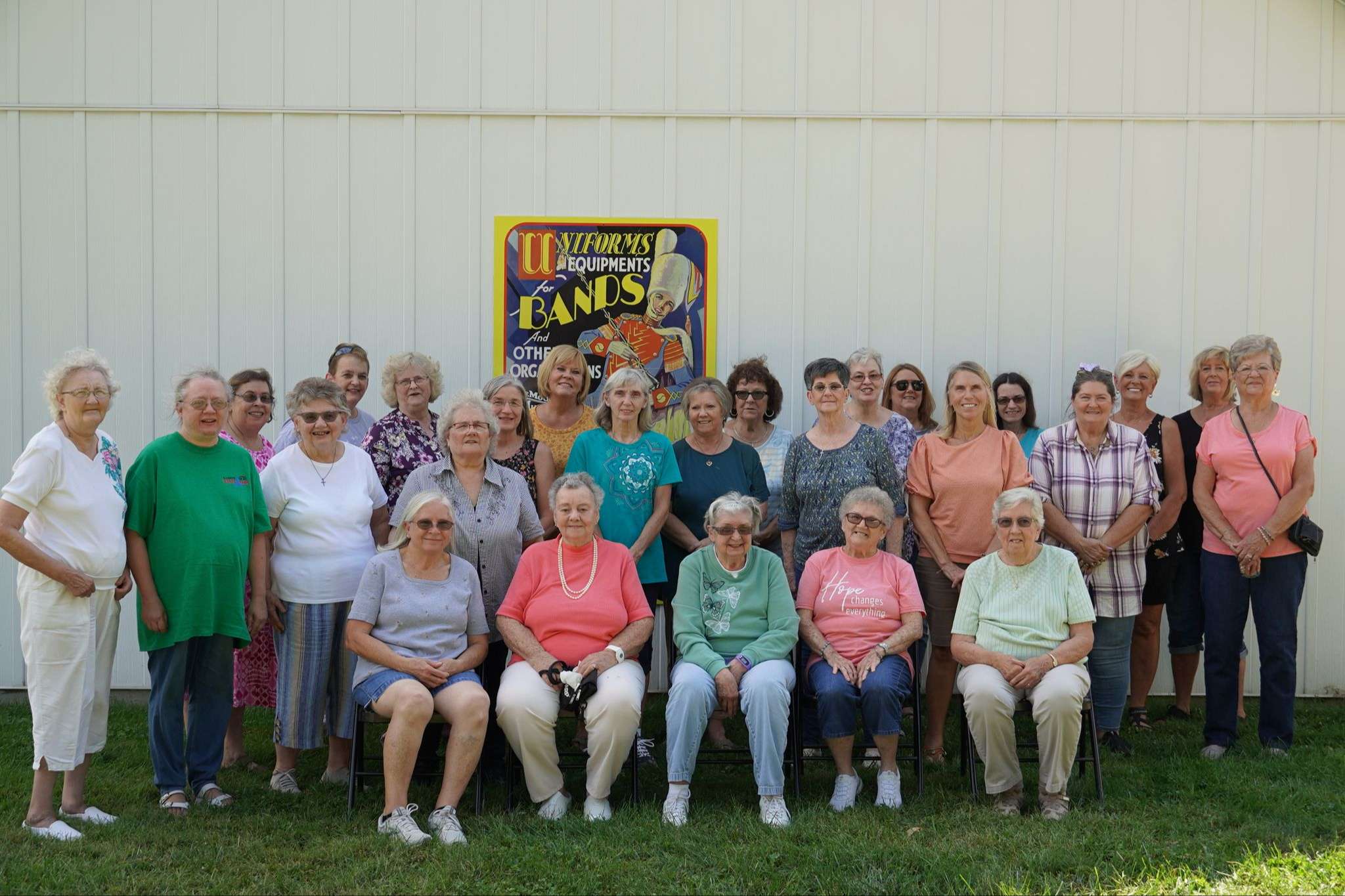 three rows of people in casual attire outside a white museum building